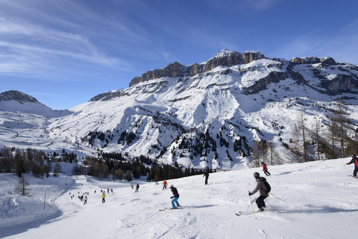 Arabba descending toward Pordoi pass, Arabba; skiers on bright snow over steep ski run in Dolomites in important ski area shutterstock_137391659.jpg